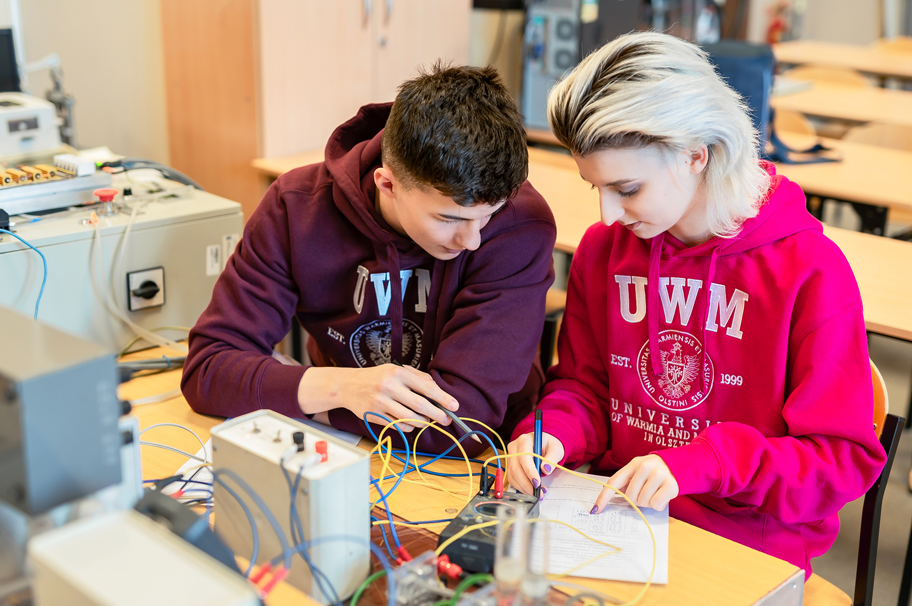 Dwie osoby pracują z przewodami i aparaturą pomiarową