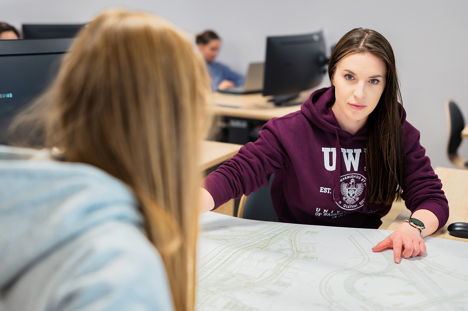 Studentki analizują mapę podczas zajęć w pracowni komputerowej