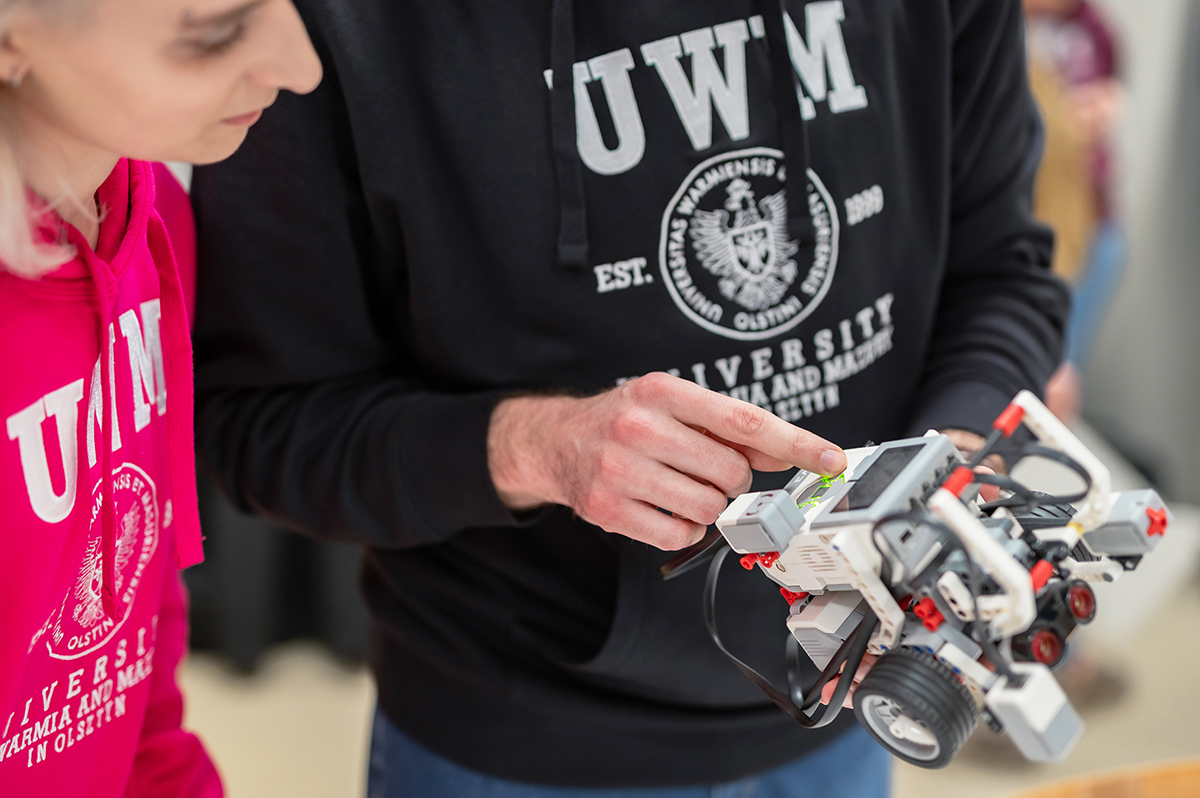 Dwie osoby oglądają robota edukacyjnego, jedna wskazuje jego element