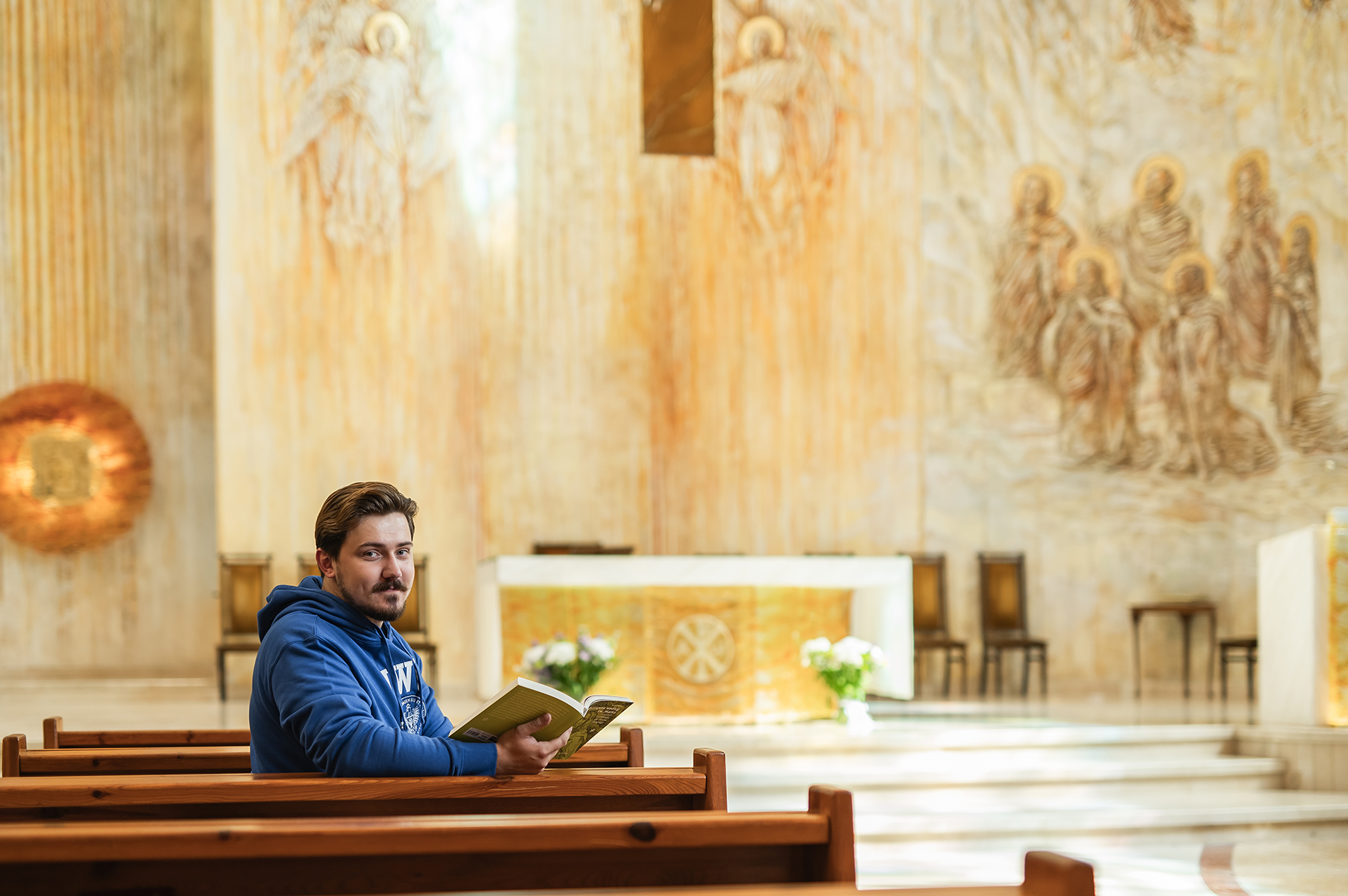 Student siedzi w ławce w kościele i czyta książkę