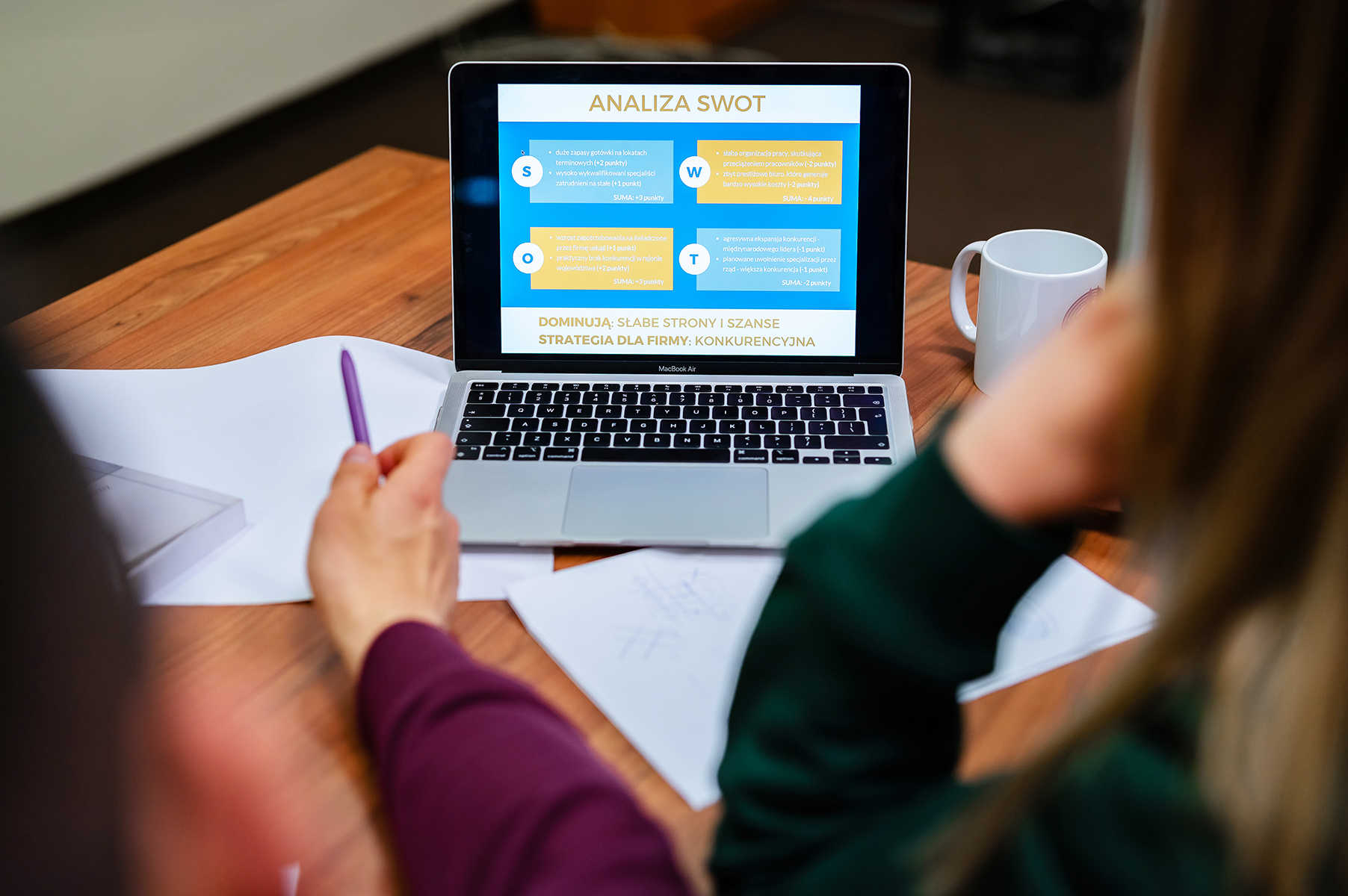 Laptop na biurku z wyświetloną prezentacją pt. „Analiza SWOT”