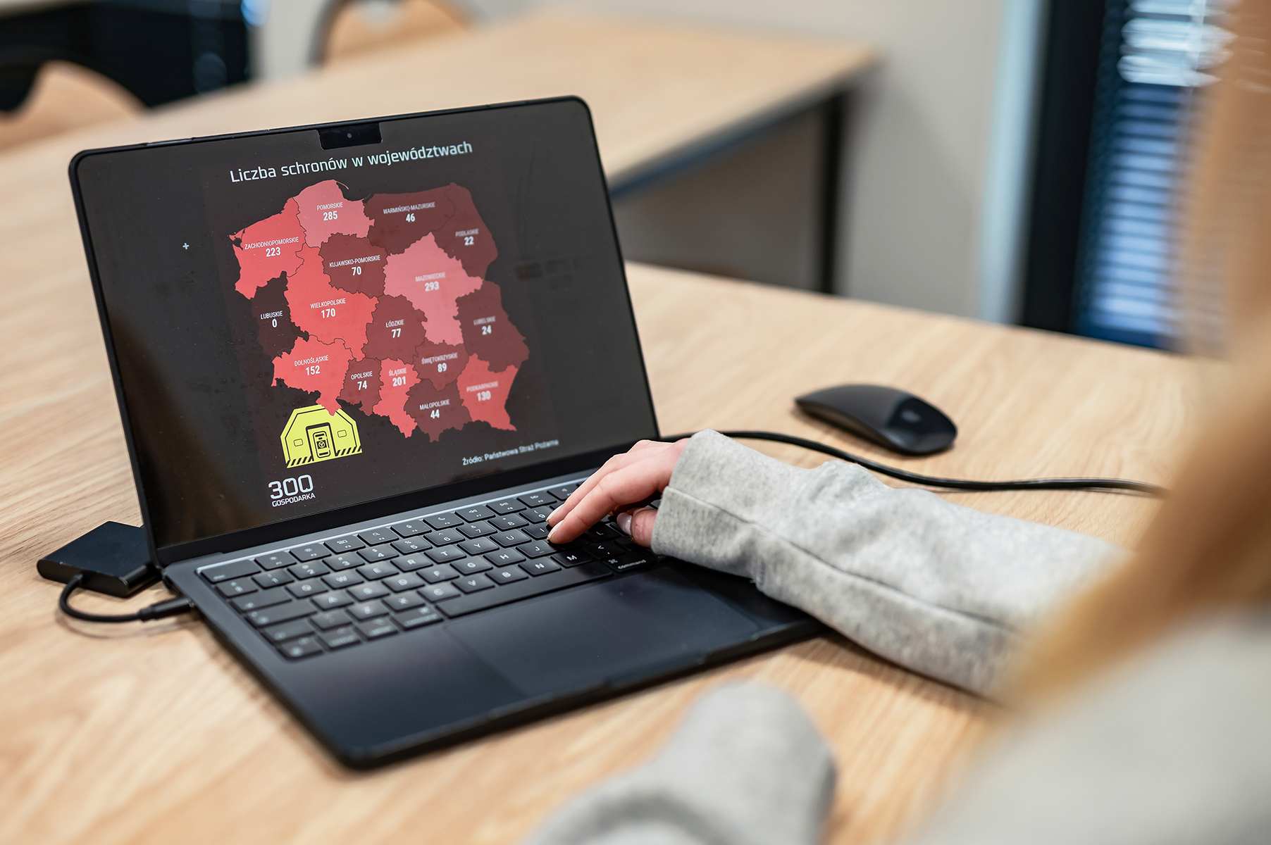 Osoba pracująca przy laptopie z mapą Polski