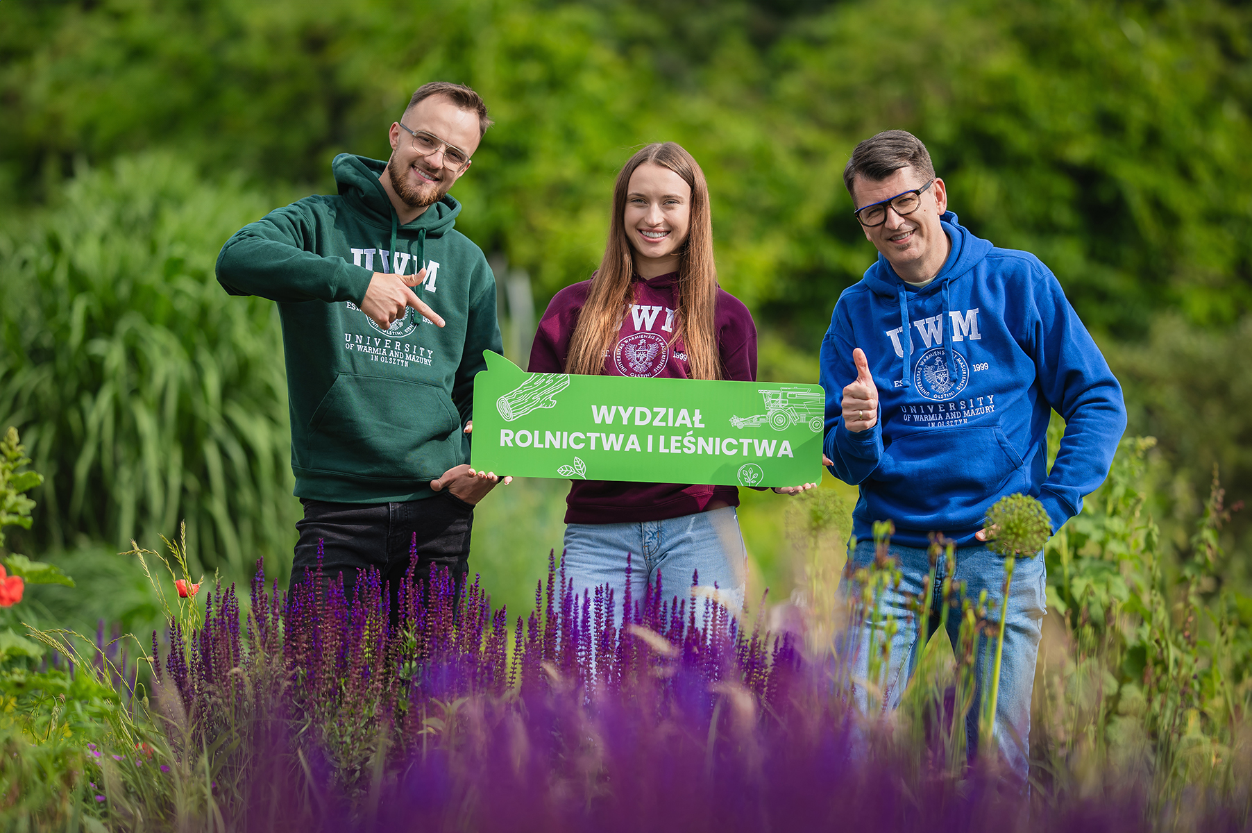 „Trzy osoby stoją w ogrodzie i trzymają tablicę z napisem „Wydział Rolnictwa i Leśnictwa”