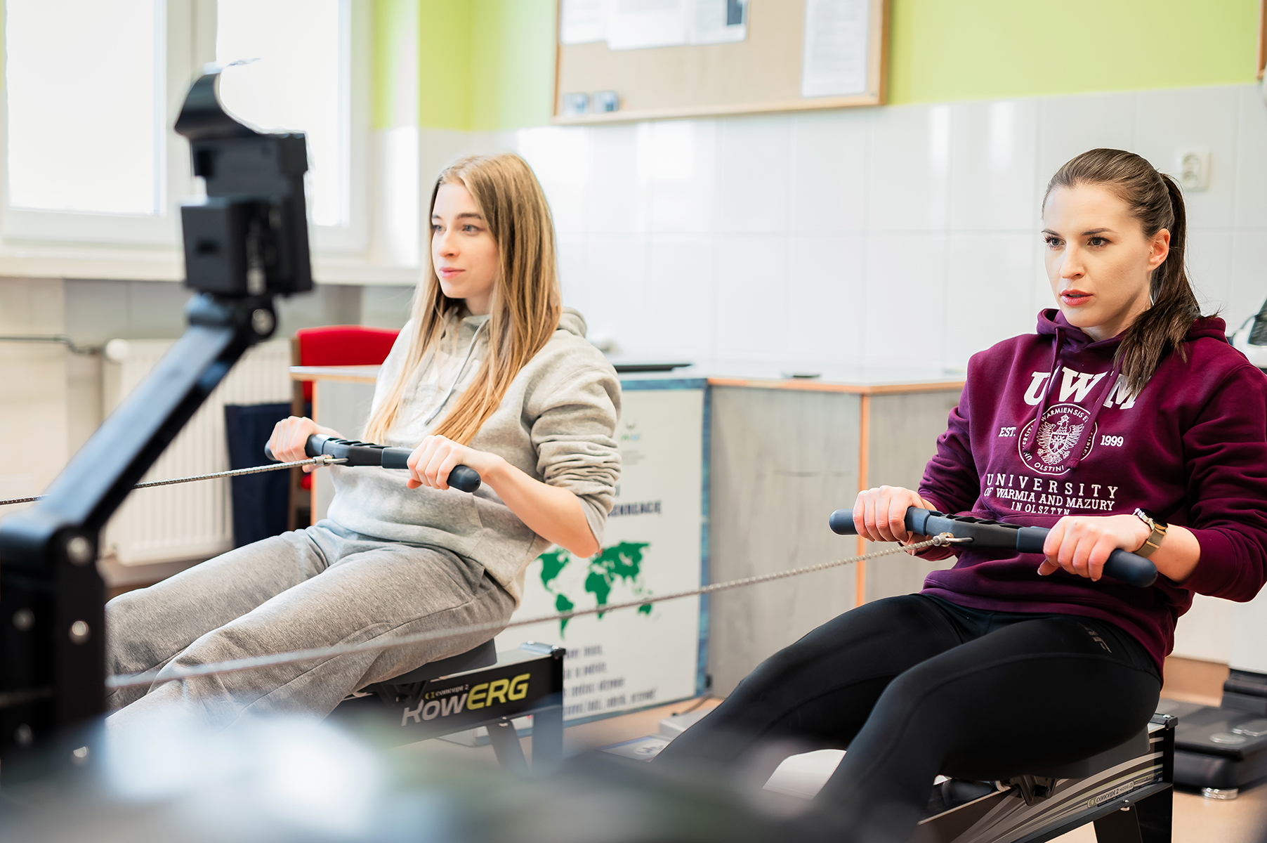 Studentki ćwiczą na ergometrach w sali treningowej