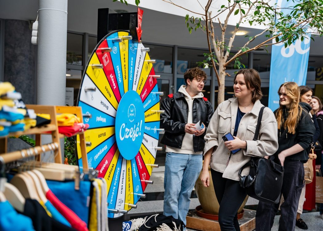 Podczas dnia otwartego kandydaci na studia ustawiają się przy kole fortuny z uczelnianymi gadżetami w holu budynku.