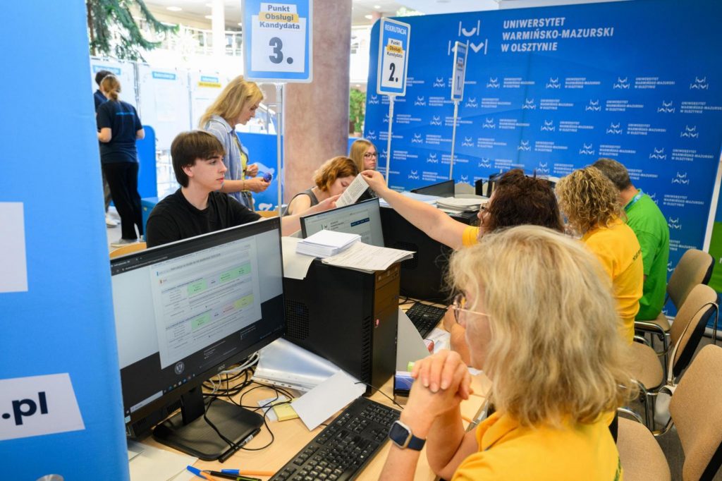 Kandydaci na studia przy stanowiskach komputerowych w punkcie obsługi podczas rekrutacji.