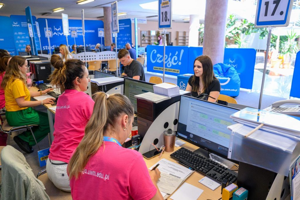 Kandydaci na studia obsługiwani przy stanowiskach komputerowych w punkcie rekrutacyjnym uczelni.